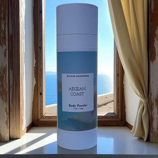 Body powder container labeled 'Aegean Coast' by Bayside Soapworks with a scenic window view in the background.