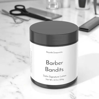 Jar of 'Barber Bandits' satin signature lotion by Bayside Soapworks on a marble surface.