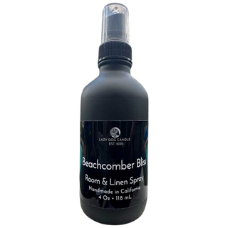 Black room and linen spray bottle labeled 'Beachcomber Bliss' by Lazy Dog Candle on a white background.