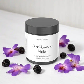 Lotion jar labeled 'Blackberry + Violet' with blackberries and purple flowers on a white background