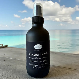Black bottle of 'Coconut Beach' room and linen spray with a beach background