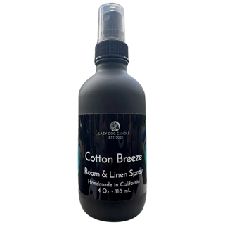 Black room and linen spray bottle labeled 'Cotton Breeze' by Lazy Dog Candle on a white background
