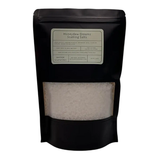 Black packaging of 'Honeydew Dreams Soaking Salts' with a clear window showing the product inside.