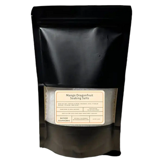 Black packaging of Mango Dragonfruit Soaking Salts with a label on a white background