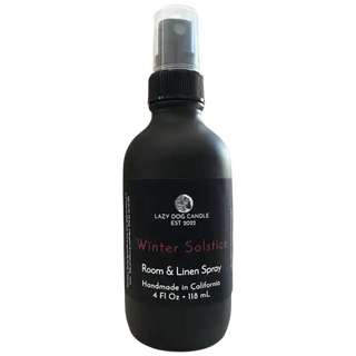 Black room and linen spray bottle labeled 'Winter Solstice' by Lazy Dog Candle on a white background