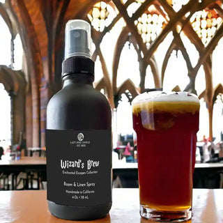 Room spray bottle labeled 'Wizard's Brew' next to a glass of dark liquid on a table with a blurred background